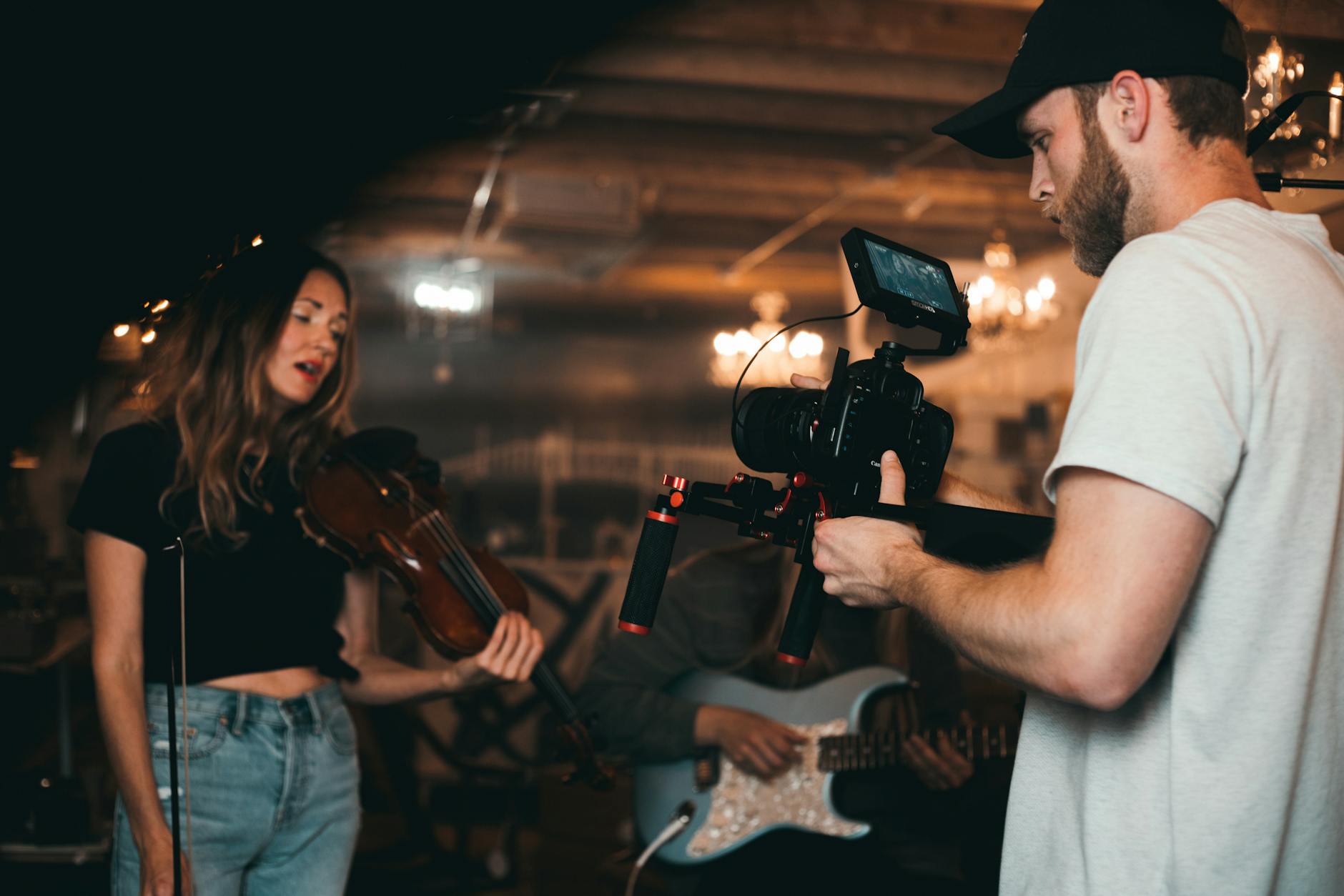 man taking a video of a woman carrying a violin