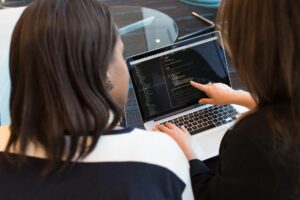 two women looking at the code at laptop